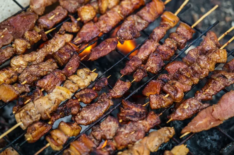 Köttspett som grillas över kol