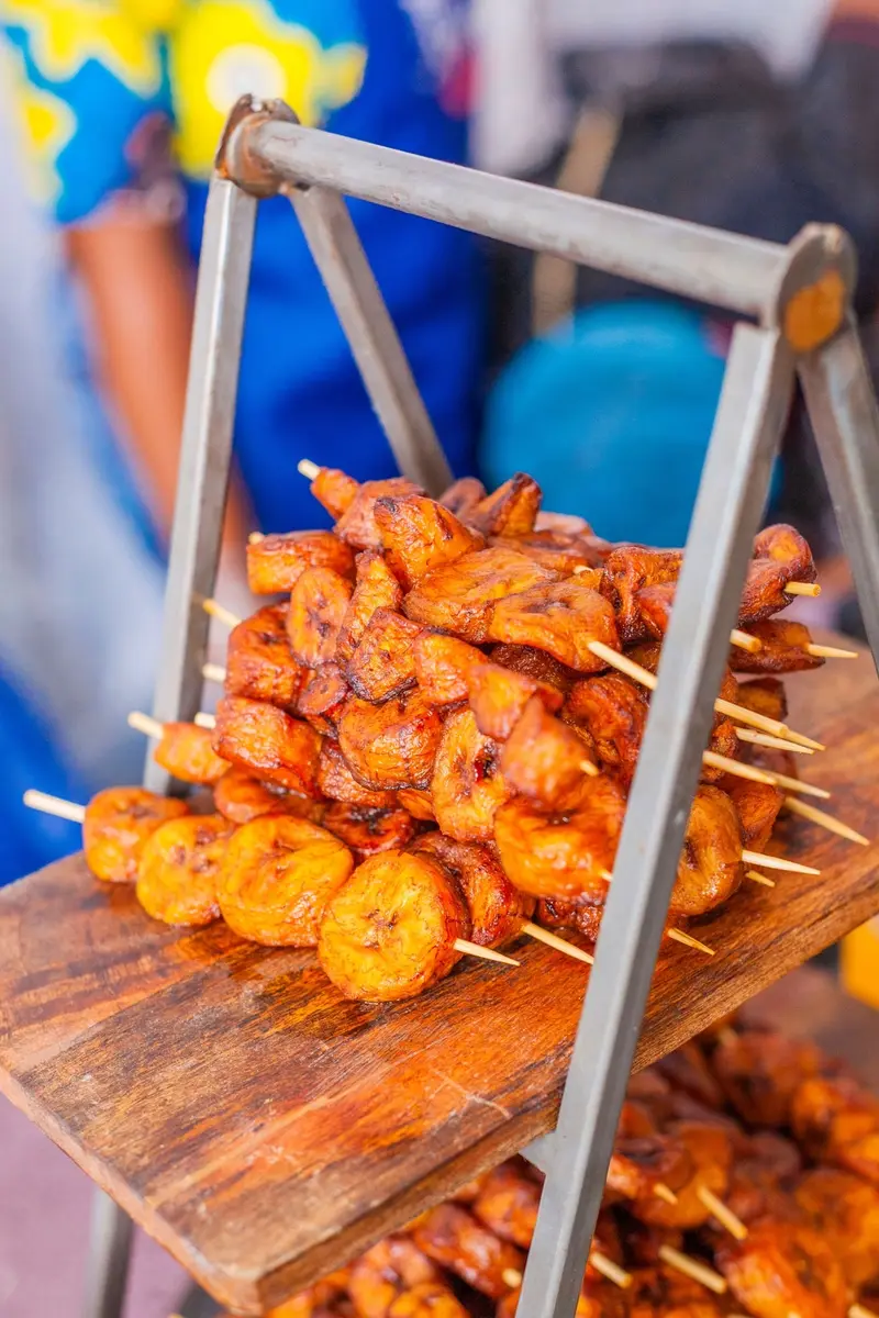 Suya-spett och stekt plantain på en träbricka